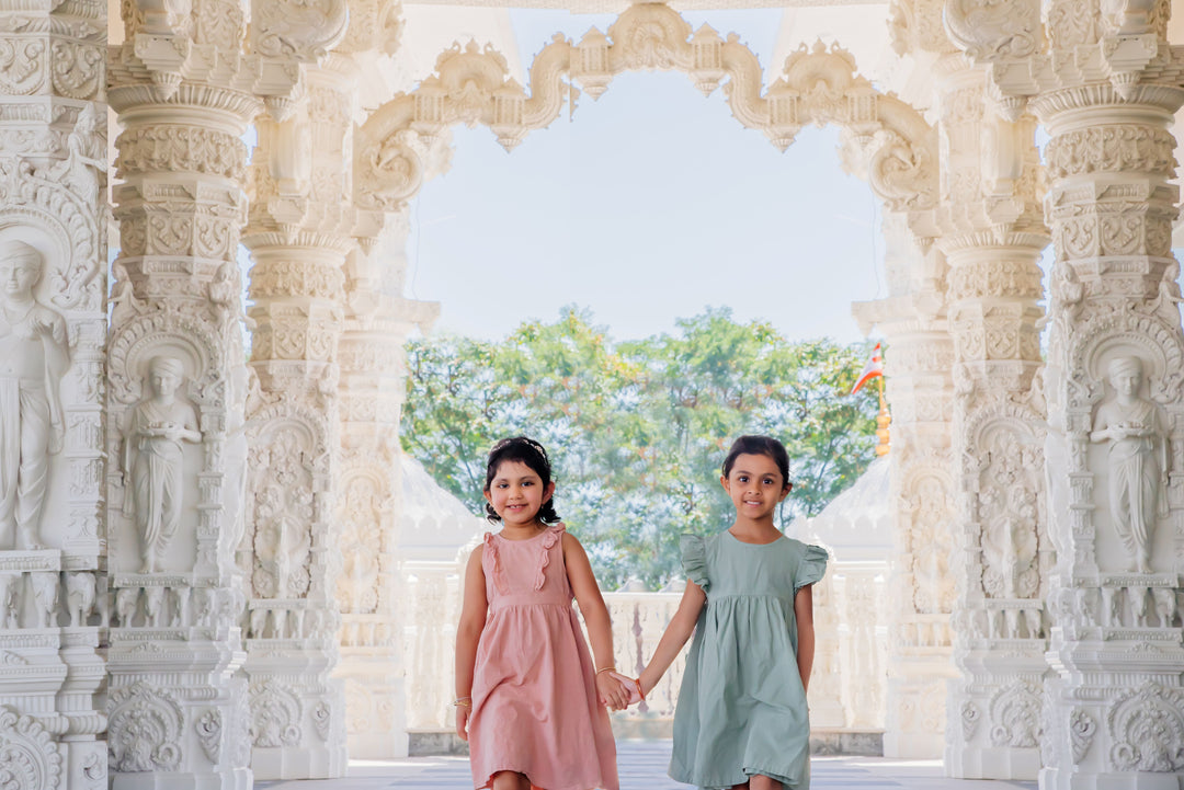 two girls holding hands walking at a hindu temple mandir