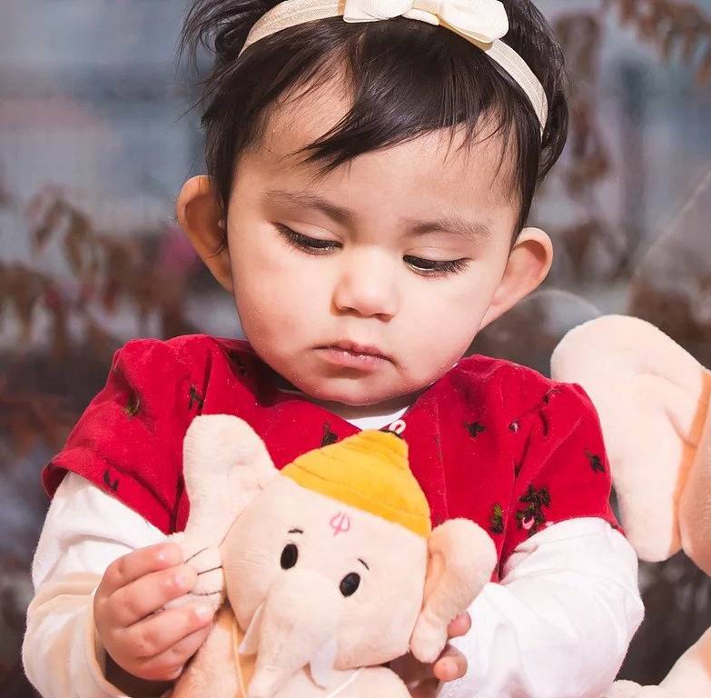 child looking at baby krishna plush toy